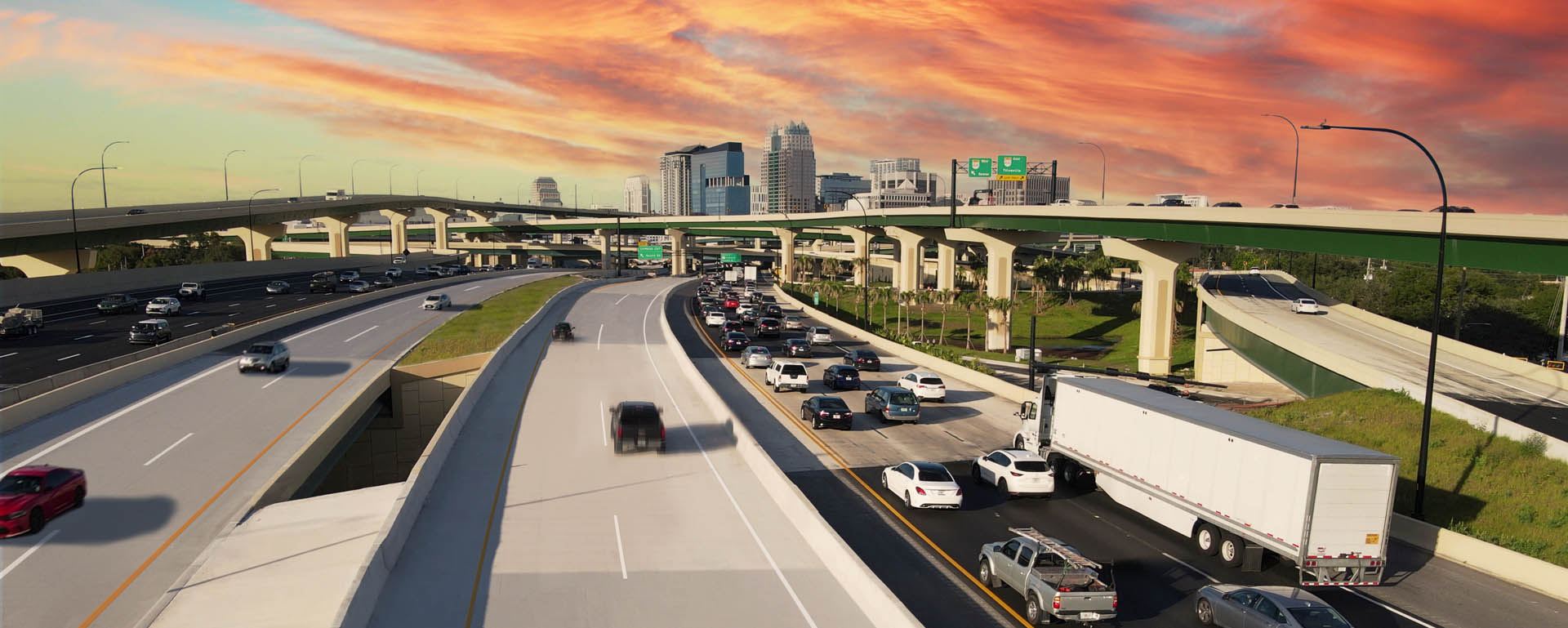 Aerial view of Interstate 4 Express lanes and overpasses leading toward the downtown Orlando skyline at sunset